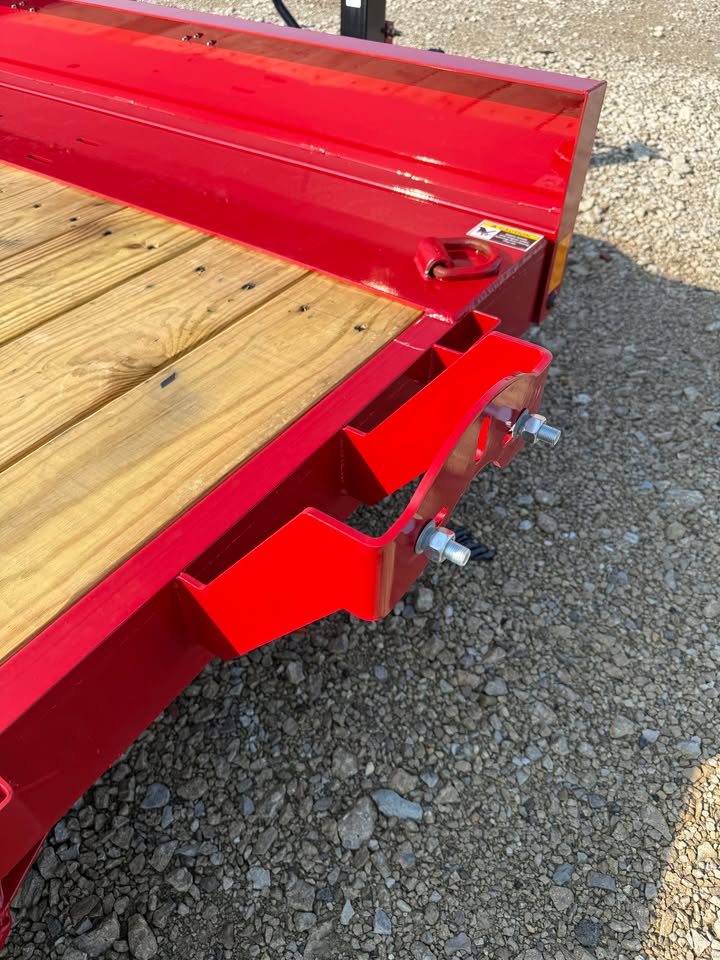 Close-up of the side bracket and wood deck on a red Load Trail 83 in x 22 ft full fender tilt trailer